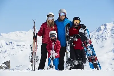 Famille avec skis et snowboards dans une station de ski en Turquie
